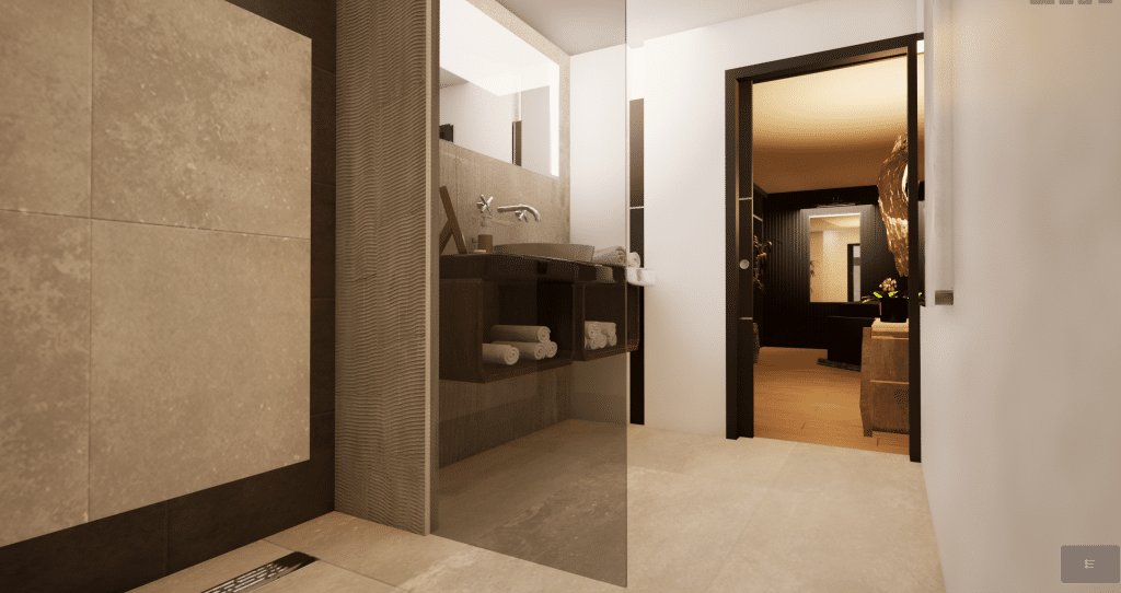 Salle de bains moderne avec des carreaux beiges, une cloison de douche en verre, un meuble-lavabo en bois foncé avec des serviettes soigneusement pliées, et une vue à travers une porte ouverte sur un couloir chaleureusement éclairé avec un vase de fleurs.